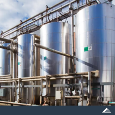 Multiple stainless steel storage tanks with industrial piping at a modern chemical processing plant, featuring CREMER North America branding.