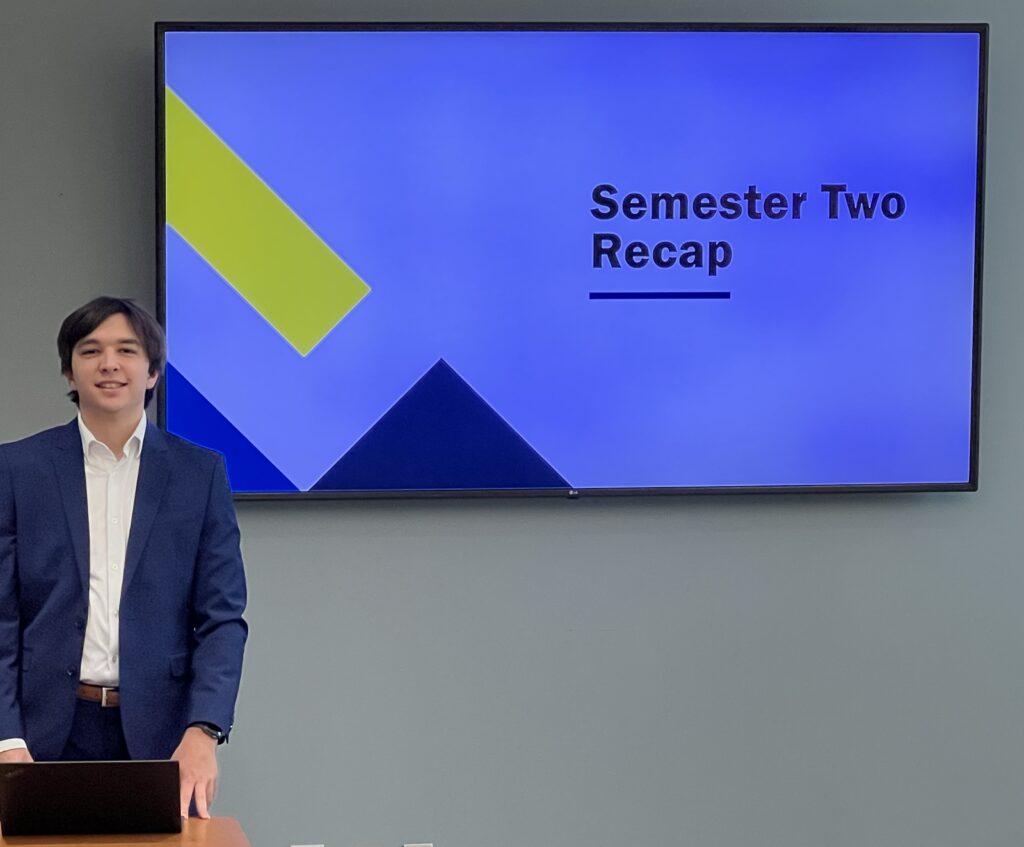 A CREMER North America intern, Jacob, who is standing near a tv monitor to present an internship presentation to leadership. Photo Credit: CREMER North America