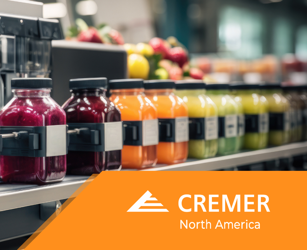 Commercial beverage production line filling bottled drinks in a food manufacturing facility with the CREMER North America logo.